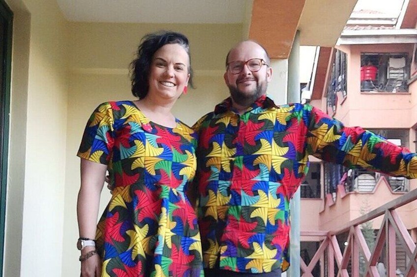 Two people standing on a balcony wearing matching colorful leaf-patterned shirts. 4