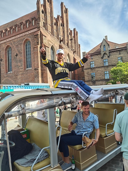 A person in a Boston jersey on a vintage car, with a historic building in the background. 5