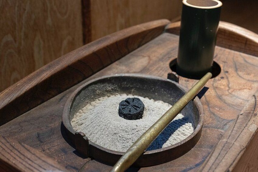 Un estufa de leña con ceniza y una taza de metal encima. 3