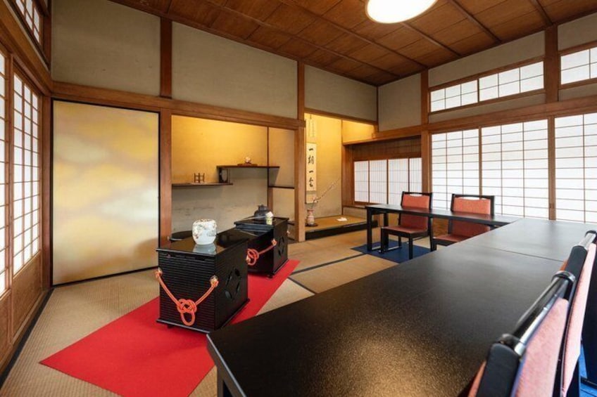 A traditional Japanese room with tatami flooring, a low table, and red cushions. 1