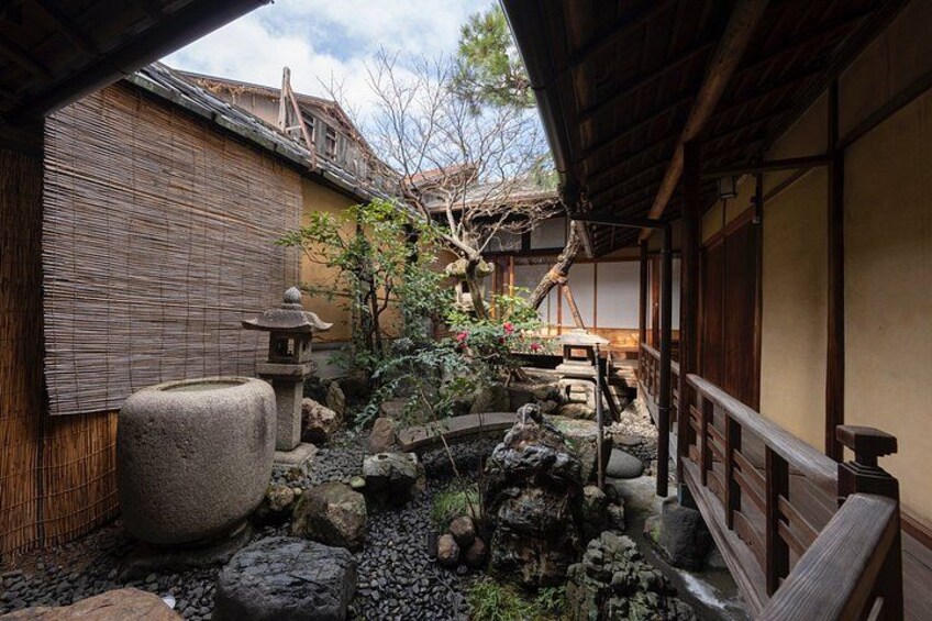 Un jardín japonés tradicional con un farol de piedra, una valla de bambú y un pequeño estanque. 2