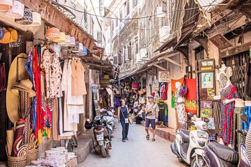 Una calle estrecha flanqueada por tiendas que exhiben diversos textiles y accesorios. 2