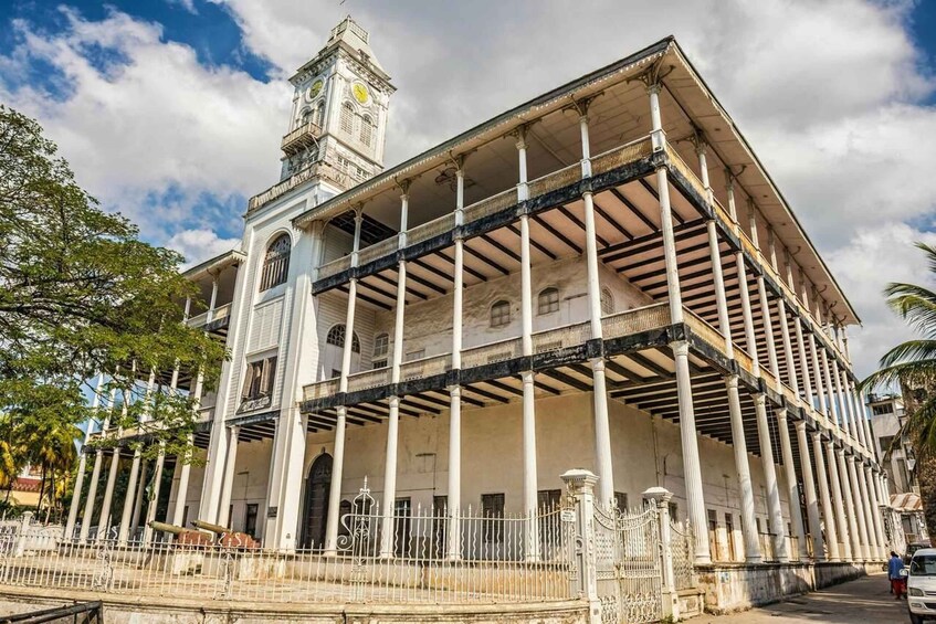 Un edificio histórico con una torre de reloj, columnas y un balcón. 5