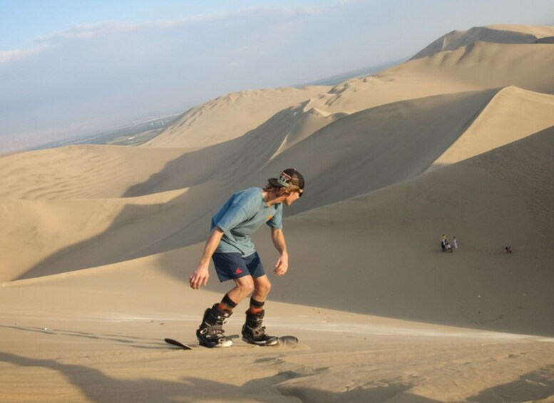 A person snowboarding down a sand dune. 3