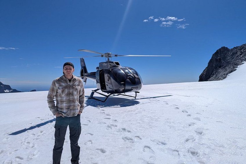 Una persona de pie sobre la nieve, con un helicóptero al fondo. 5
