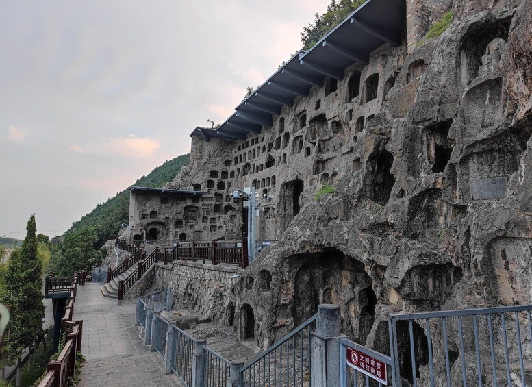 A rock formation with multiple caves and a staircase leading up to a building. 2