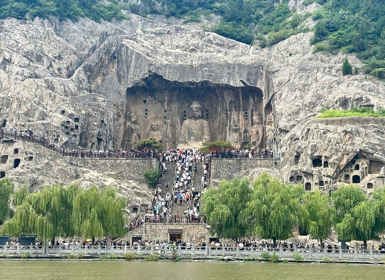 A large Buddha statue carved into a cliff face with a staircase leading up to it. 3