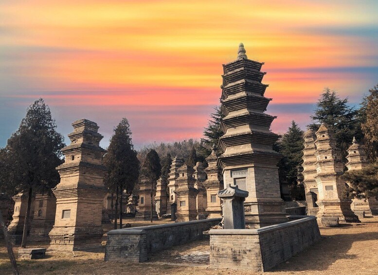 A collection of ancient stone pagodas at sunset. 4