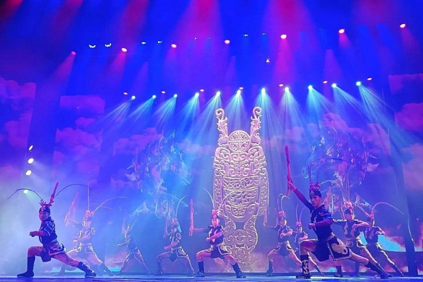 A stage with performers in elaborate costumes, a large ornate chair, and dramatic lighting. 2