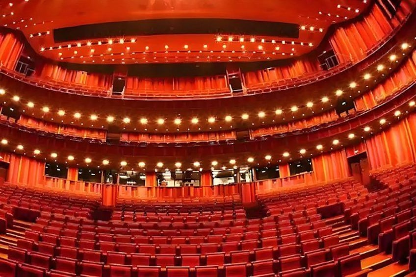 A multi-tiered theater with rows of red seats and a circular stage. 3