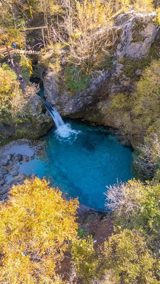 A waterfall in a forested area with clear blue water. 4