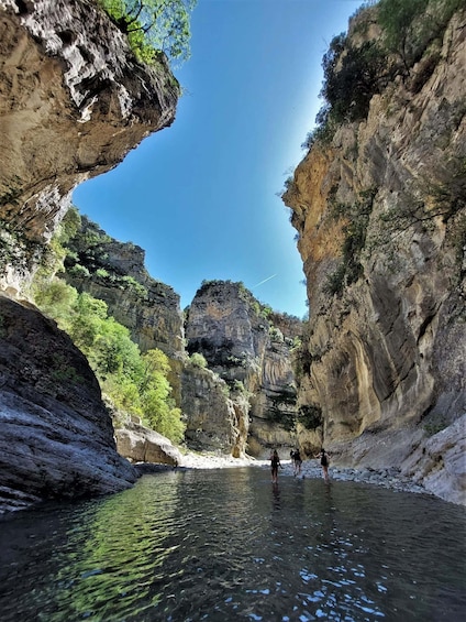 A canyon with a river, rocky cliffs, and a clear blue sky. 3