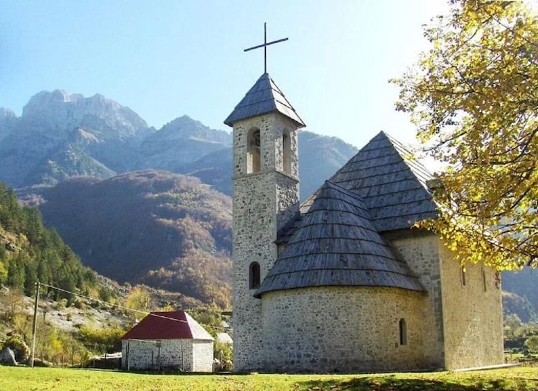 A church with a bell tower and a smaller building in a mountainous area. 5