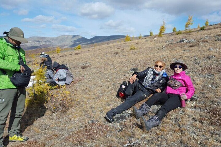 People sitting on a grassy hill with mountains in the background. 5