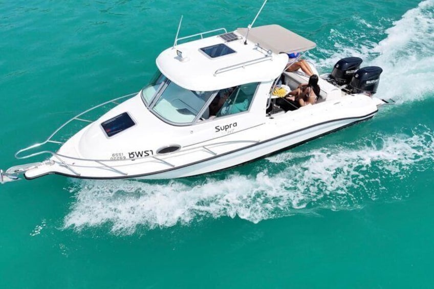 A white boat named 'Supra' with the registration number 'WSI' on turquoise water. 1