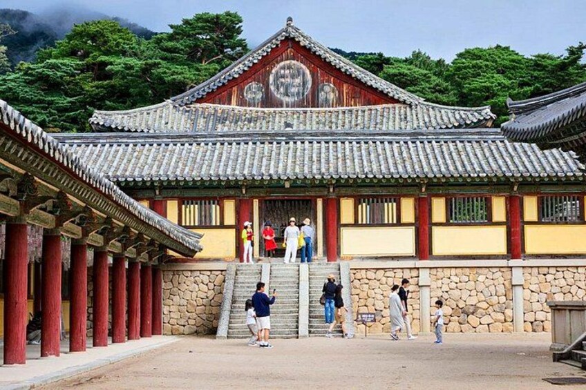 A traditional Korean building with a tiled roof, stone columns, and a stone wall. 5