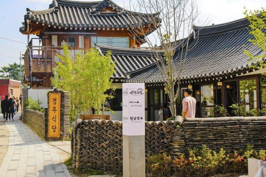 Edificio tradicional coreano con tejado de tejas, pared de piedra y un cartel. 2