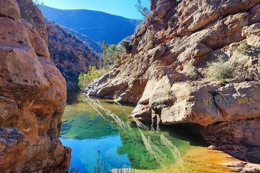 Un canyon con un corso d'acqua limpida, pareti rocciose e una montagna sullo sfondo. 4