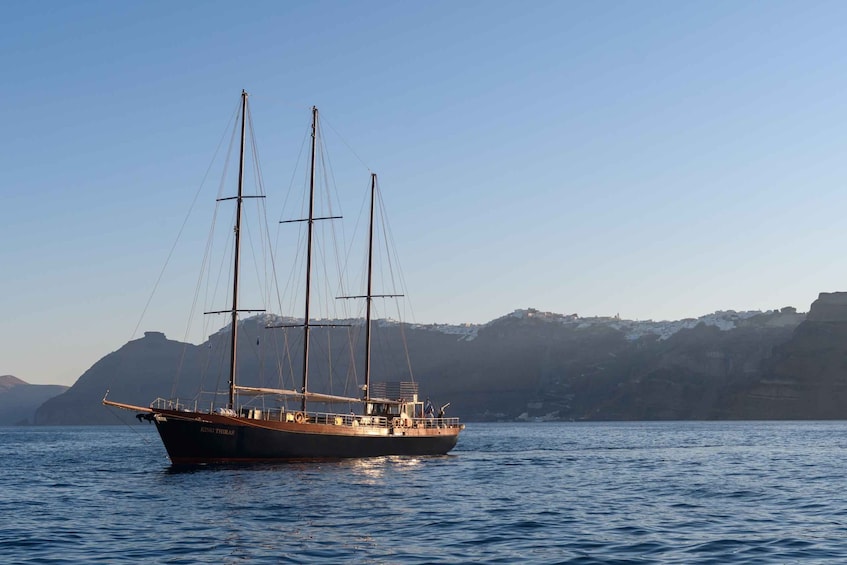 A sailing ship named 'King Thras' on calm waters with a mountainous coastline in the background. 1