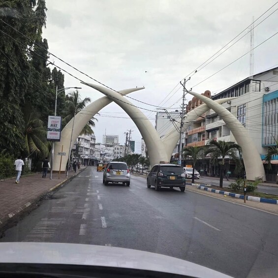 A street with cars, palm trees, and buildings with unique arches. 3