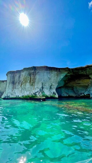 A clear blue sky, a large white cliff, and turquoise water. 4