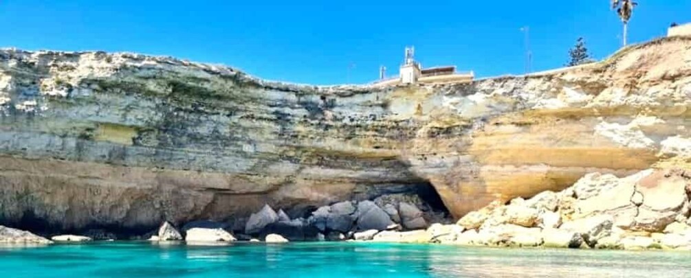 A coastal cliff with a rocky shoreline and a clear blue sea. 5