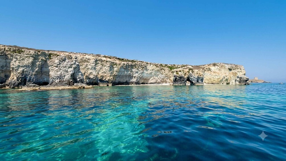 A coastal landscape with clear blue waters, rocky cliffs, and a small boat in the distance. 2