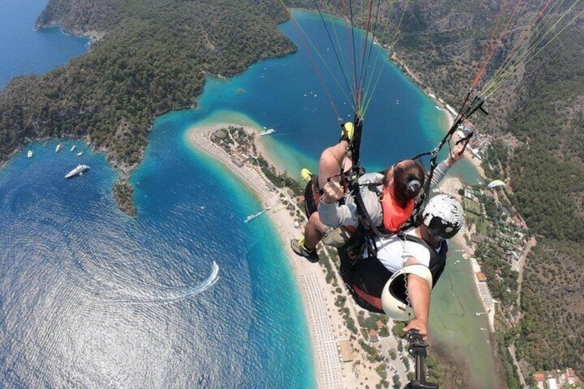Una persona haciendo parapente sobre una zona costera con aguas azules cristalinas y una playa. 4