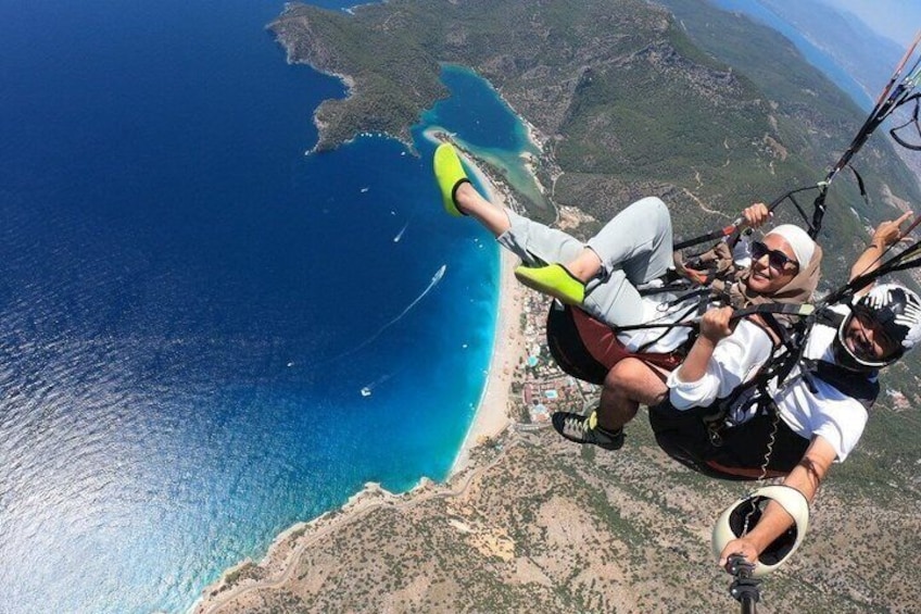 Dos personas haciendo paracaidismo sobre un paisaje costero con una playa y montañas al fondo. 5
