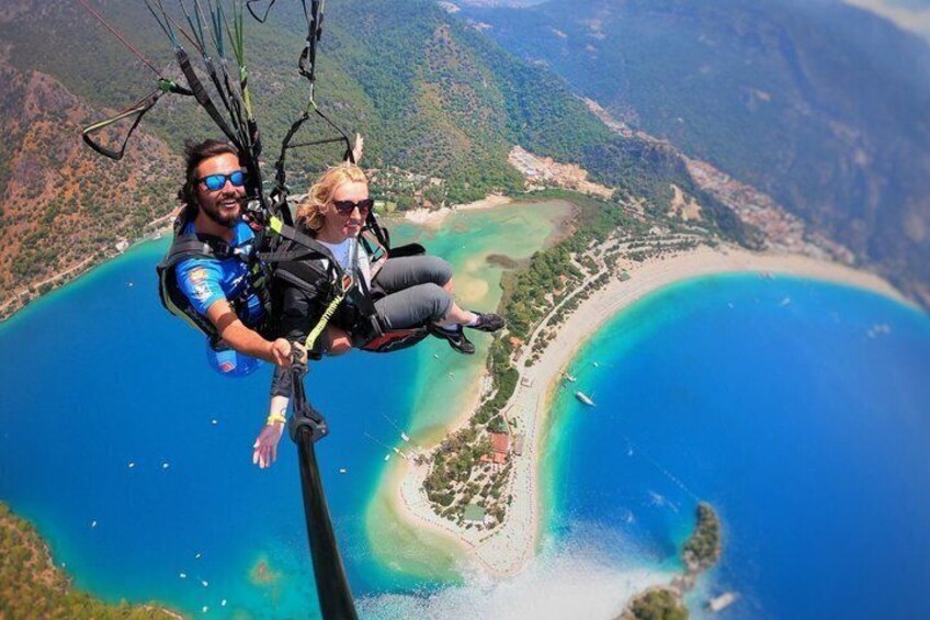 Una persona haciendo paracaidismo sobre una zona costera con aguas azules cristalinas y una playa. 3