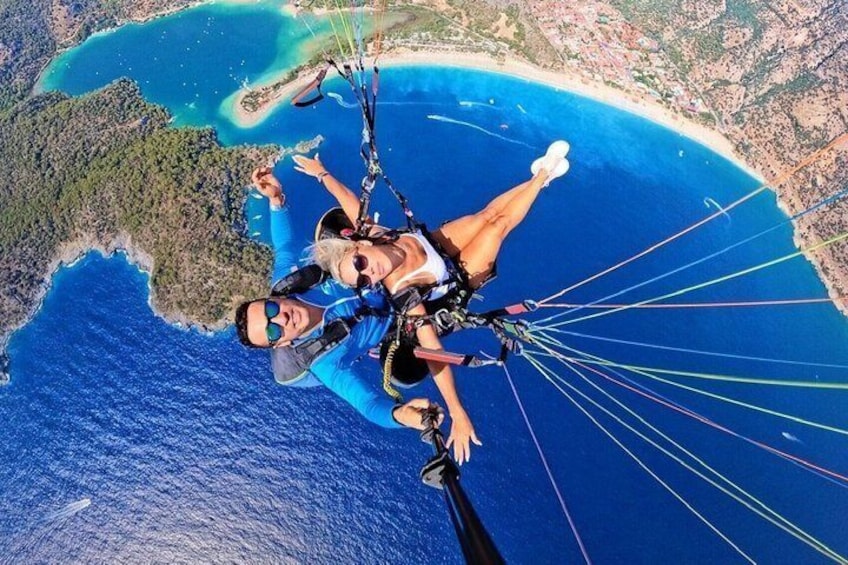 Una persona practicando parapente sobre una zona costera con aguas azules cristalinas y una playa. 1