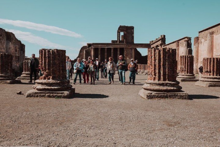 Ancient ruins with columns and a temple-like structure in the background. 4