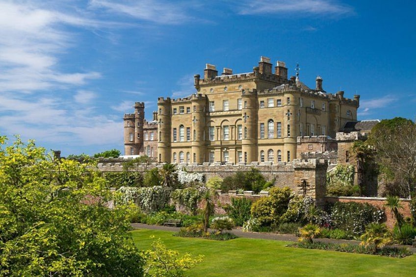 A large, historic building with multiple towers and a well-maintained garden. 1