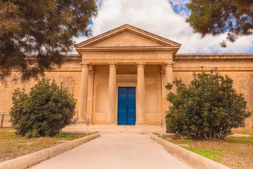 A neoclassical building with a blue door and columns, surrounded by trees. 5