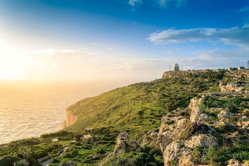 A coastal landscape with a cliff, greenery, and a building with a dome. 3