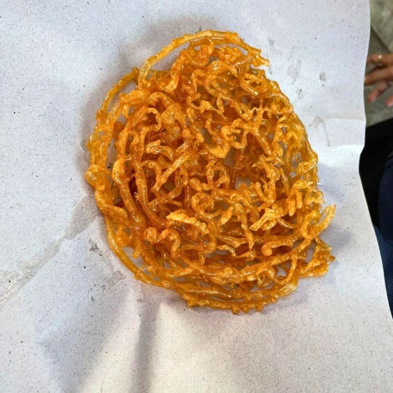 A pile of orange, crispy, spiral-shaped food items on a white surface. 4