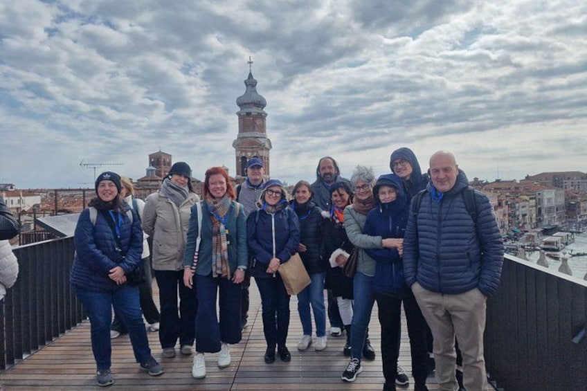 A group of people on a wooden bridge with a cityscape and a tower in the background. 4