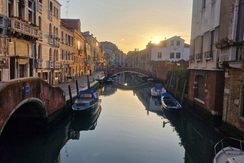 A canal with boats, a bridge, and buildings along the water. 3