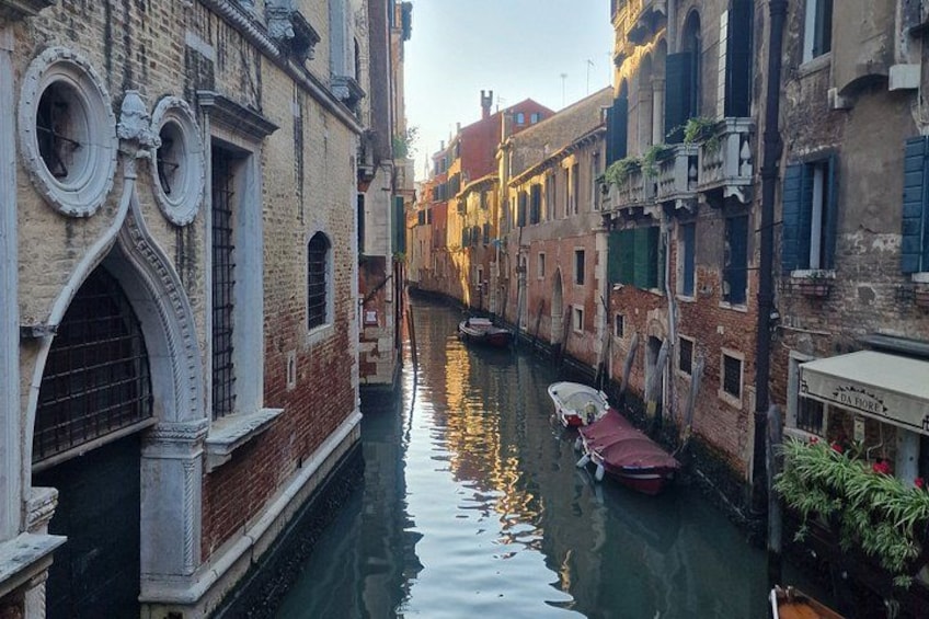 A narrow canal in Venice with boats and historic buildings. 5