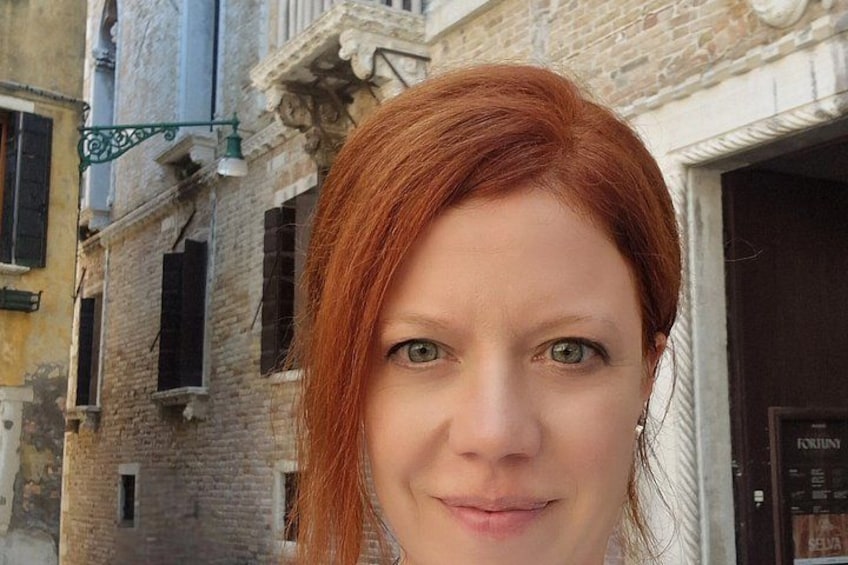 A person with red hair standing in front of a building with a door labeled 'FORUM.' 2