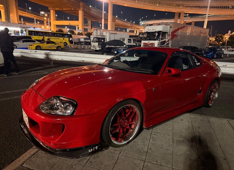 A red sports car parked at a toll booth at night. 5