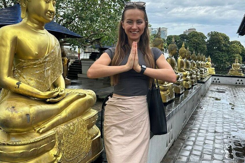 Una persona de pie frente a una hilera de estatuas doradas de Buda. 2