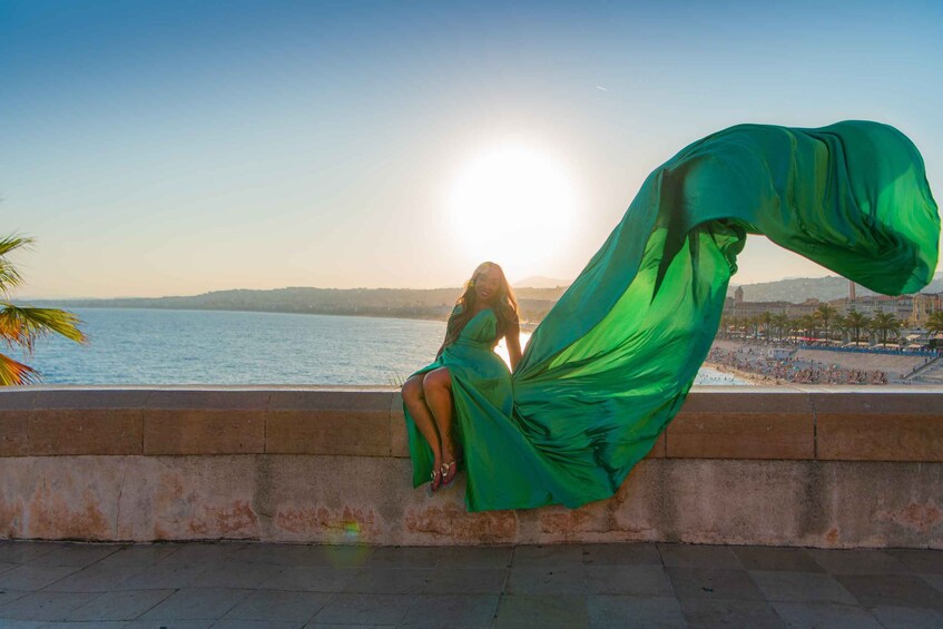 A person sitting by a waterfront with a green dress flowing in the wind. 2