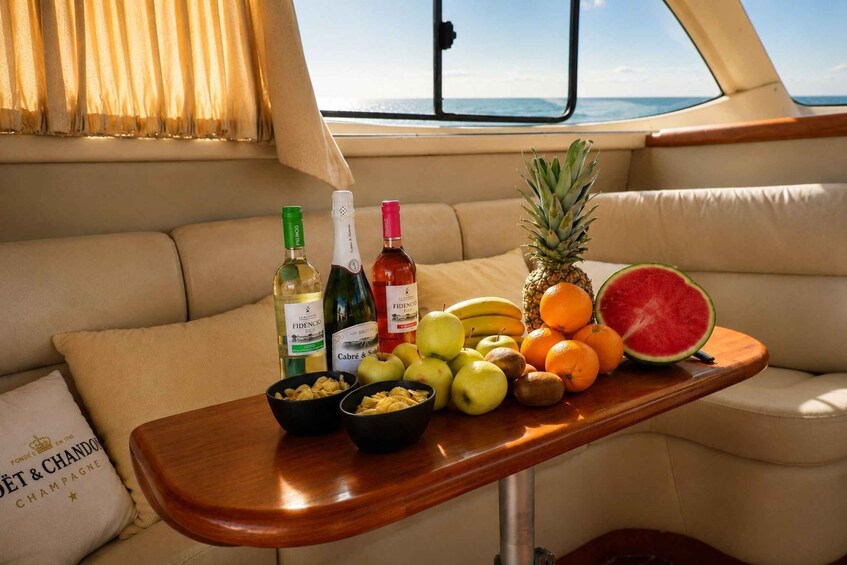 A boat interior with a wooden tray holding fruits, bottles, and a pillow. 3