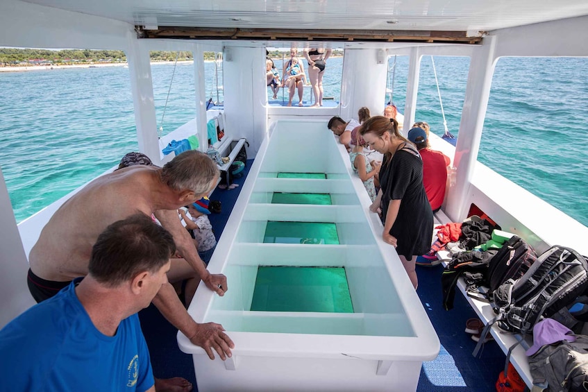 A boat with a central aisle and passengers standing at the back. 1