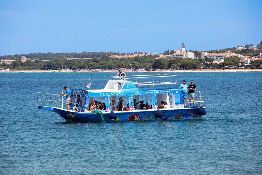 A glassboat tour with passengers and a guide on a calm sea, with a coastal town in the background. 2