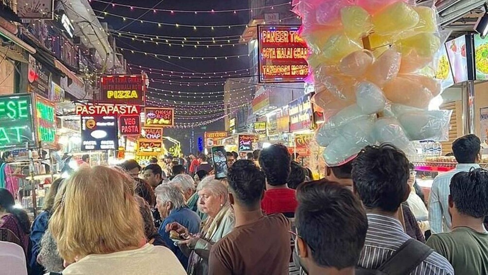 A crowded street market with various food stalls, including one for pizza and another for pasta. 4