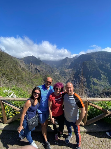 A group of people standing on a wooden platform with a mountainous landscape in the background. 3