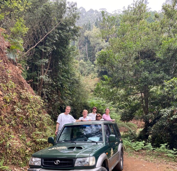 A green SUV parked on a dirt path surrounded by dense greenery and trees. 3