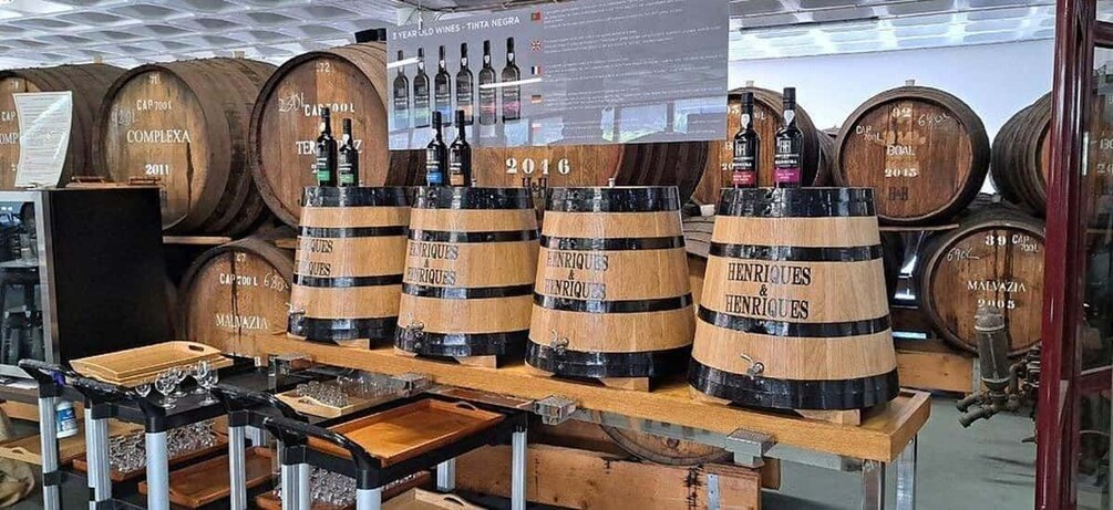 Wooden barrels labeled with names and years, arranged on a wooden table in a storage area. 2